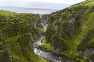 Green mossy cliff with river in Iceland. Join The Travel Yogi for your bucket list travel. Photo credit: Serey Morm