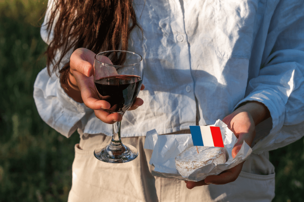 Woman holding a glass of French wine and cheeses. Why is French wine so good? Read to find out. Photo: Paulina Kovaleva