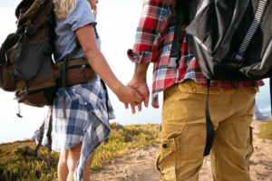 Backpacking couple holding hands. Explore the world’s most romantic places with The Travel Yogi.