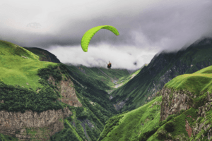 Two people paragliding over mountains. Discover adventurous couples vacations with The Travel Yogi. Photo: Katerina Kerdie