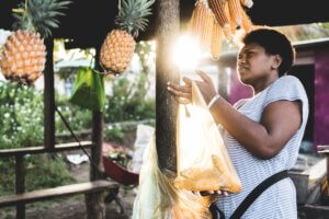 woman inspects a pineapple in the market in Fiji