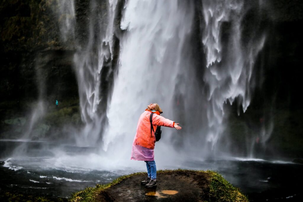 Joyful woman standing under a waterfall by Daria Gordova via Unsplash.