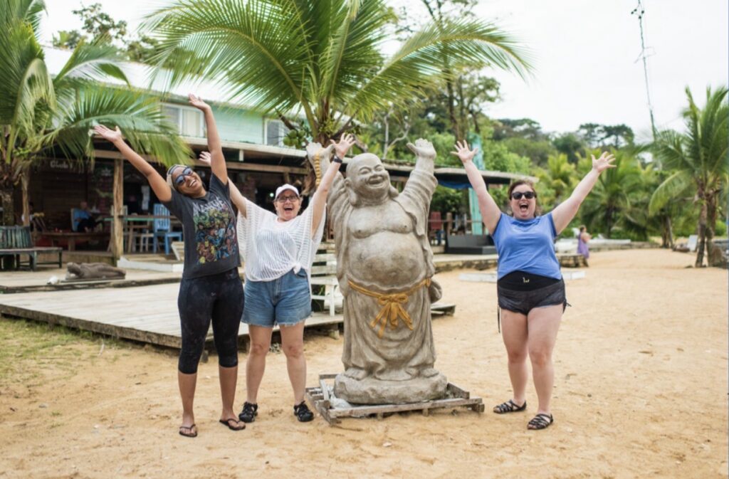 Travelers throwing their hands up in Panama next to a statue