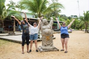 Travelers throwing their hands up in Panama next to a statue